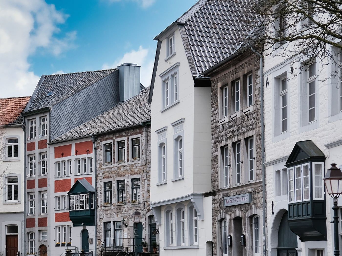 Reihe historischer Stadthäuser mit Erkern, Putz und Bruchsteinfassaden an einem Marktplatz